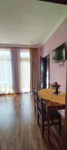 una sala da pranzo con tavolo in legno e una camera con pareti rosa di Hotel TWINS ANNA a Kobuleti