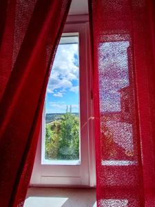 een raam in een kamer met een rood gordijn bij La Finestra sul Corso in Bucchianico