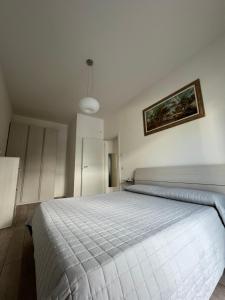 a bedroom with a white bed with a painting on the wall at Appartamento Noi Due in Riva del Garda