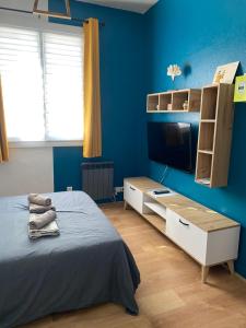 - une chambre avec des murs bleus, un lit et une télévision dans l'établissement Les délices du Havre 15 min du centre ville et de la mer, au Havre