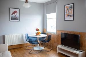 a living room with a table and a tv at Beautiful Seafront Apartment-Hastings Old Town 2+2 in Hastings