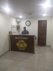 um homem atrás de uma recepção num quarto em Hotel Paradise, Patiala em Patiala