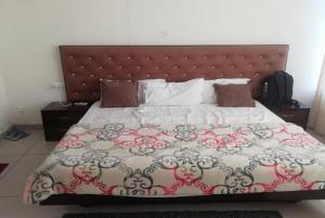 um quarto com uma cama grande e uma grande cabeceira. em Hotel Paradise, Patiala em Patiala
