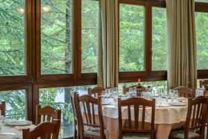 una sala da pranzo con tavoli, sedie e finestre di Ovindoli Park Hotel & SPA a Ovindoli
