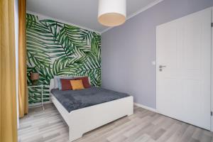 une chambre avec un lit avec un mur de feuilles vertes dans l'établissement A.S. HOME Kosciuszki, à Wrocław