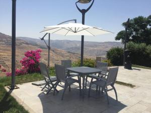 a table and chairs with a white umbrella at Mountain Pool Suites in Amman