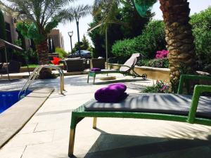 a green bench with a purple pillow on it next to a pool at Mountain Pool Suites in Amman