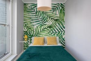 a bedroom with a green bed and a green leafy wall at A.S HOME Kościuszki II in Wrocław