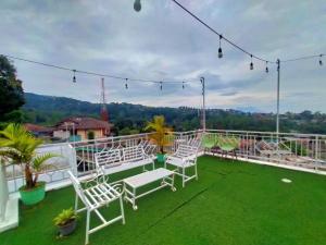 Villa Cisarua Zeni 1 في Brujul: شرفة مع كراسي بيضاء على عشب أخضر