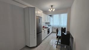 cocina con armarios blancos y nevera de acero inoxidable en Nordic Residence 28 en Suceava