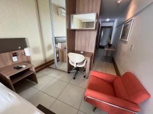 a hotel room with a red couch and a desk at Brasil flats - Athos Bulcão in Brasilia