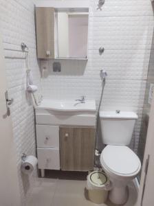 y baño con aseo blanco y lavamanos. en Kata Suites Floripa, en Florianópolis