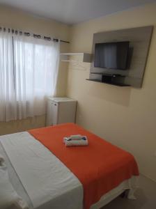 1 dormitorio con 1 cama y TV en la pared en Kata Suites Floripa, en Florianópolis
