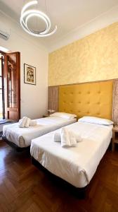 duas camas num quarto de hotel com lençóis brancos em Romerooms Condotti em Roma
