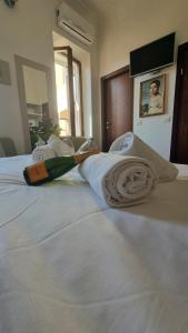 uma cama com uma garrafa e toalhas em Romerooms Condotti em Roma