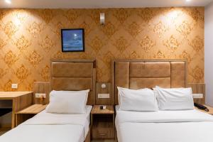ムンバイにあるLOTUS GRAND HOTEL MUMBAIのベッド2台、壁掛けテレビが備わるホテルルームです。