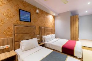 ムンバイにあるLOTUS GRAND HOTEL MUMBAIのベッド2台、壁掛けテレビが備わるホテルルームです。