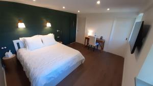 een slaapkamer met een wit bed en een groene muur bij Petit Manoir Proche Dinan in Lanvallay