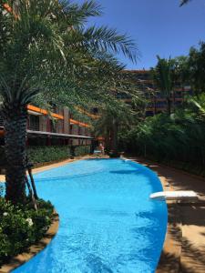 a swimming pool with palm trees in front of a building at Mai Khao Beach Apartments in Mai Khao Beach