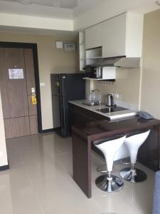a kitchen with a sink and a counter with two bar stools at Mai Khao Beach Apartments in Mai Khao Beach