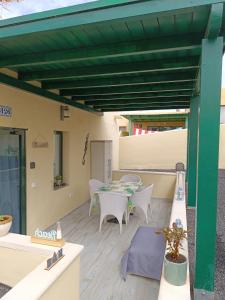 pérgola verde con mesa y sillas en el patio en El Caseton en Costa Calma