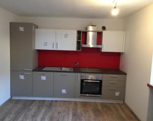 una cucina con armadietti bianchi e parete rossa di Casa Fabiolin a Daiano