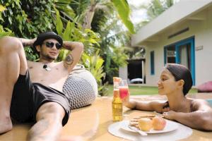 Un uomo e una donna seduti a un tavolo con un drink di Sleepy Gypsea Villa Siargao - Private Room - Daydream a Catagnan