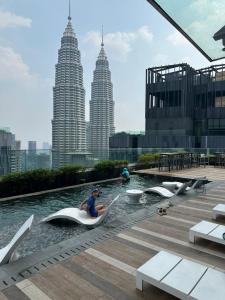 a woman sitting on a boat in a pool with buildings at KLCC Ritz Residence STAR in Kuala Lumpur