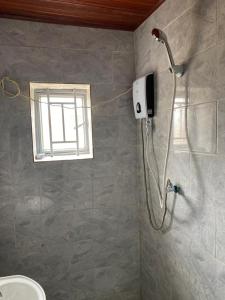 a shower in a bathroom with a window at KANOMBE AIRPORT BED& BREAKFAST in Kigali