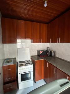 a kitchen with a white stove and wooden cabinets at KANOMBE AIRPORT BED& BREAKFAST in Kigali