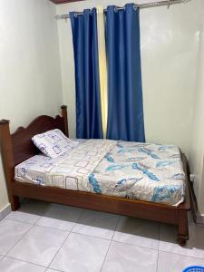 a bedroom with a bed with a blue curtain at KANOMBE AIRPORT BED& BREAKFAST in Kigali