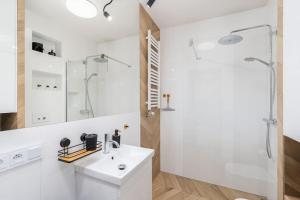 a white bathroom with a sink and a shower at BlueApart Mogilska in Kraków
