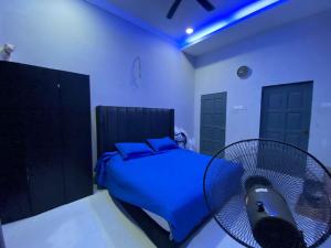 - une chambre avec un lit bleu et un ventilateur dans l'établissement homestay kuala kedah, à Kuala Kedah