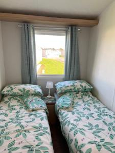 2 Betten in einem kleinen Zimmer mit Fenster in der Unterkunft Lakeside in Chichester