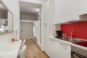 una cocina con armarios blancos y una pared roja en Apartments Trieste Centro I Imbriani 12/B, en Trieste