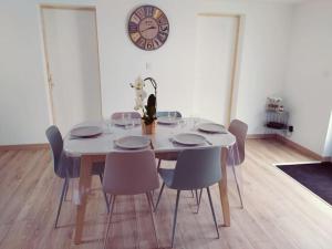 mesa de comedor con sillas y reloj en la pared en T3 - Appartement jardin Wissant 6 personnes, en Wissant