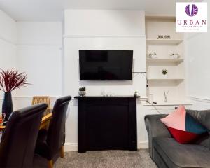 a living room with a couch and a tv on a wall at 4 Bedroom House, Perfect For Business , Relocation, Contractors, Families By Urban Luxury Stays Short Lets & Serviced Accommodation Liverpool & Free Parking in Liverpool