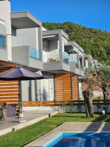 a house with a swimming pool and an umbrella at Sol Greco Apartment in Skala Rachoniou