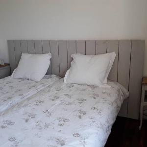 ein Bett mit zwei Kissen und einer weißen Decke in der Unterkunft Gîte breton au bord du GR34 in Landunvez