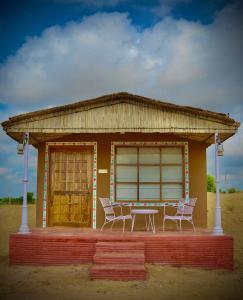a small building with a table and chairs in front of it at Bikaner Desert Camp and Resort in Bikaner