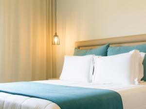 un letto con 2 cuscini bianchi e una coperta blu di Santa Cruz Boutique Hotel a Mindelo