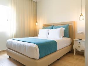 Schlafzimmer mit einem großen Bett mit blauer und weißer Bettwäsche in der Unterkunft Santa Cruz Boutique Hotel in Mindelo
