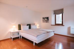 a white bedroom with a bed and a window at Bigatt Hotel & Restaurant in Lugano