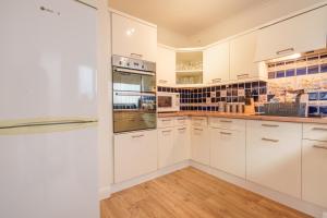 a kitchen with white cabinets and wooden floors at Offa's Lodge Family home quiet area with sea views in Prestatyn