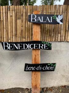 a wooden pole with signs on it next to a fence at Balai Benedicere Bed & Breakfast in Bacnotan
