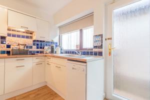 a kitchen with white cabinets and a window at Offa's Lodge Family home quiet area with sea views in Prestatyn