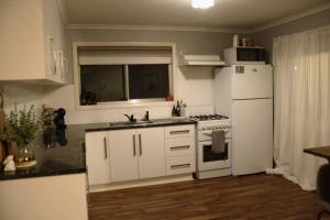 een keuken met witte kasten en een witte koelkast bij Gum Lodge, Gateway to the Murray in Loxton