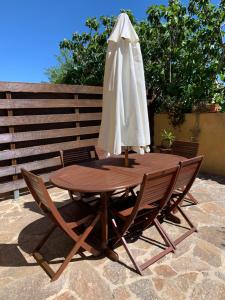 een houten tafel met een witte parasol en 2 stoelen bij Villa les Pensées La Londe in La Londe-les-Maures