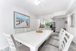 a white dining room with a white table and chairs at Just Beachy By Beachside Management in Siesta Key