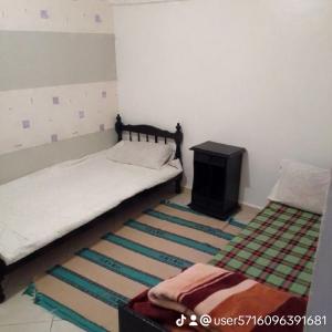 1 dormitorio con cama, mesa y alfombra en المنظر الجميل, en El Ksiba